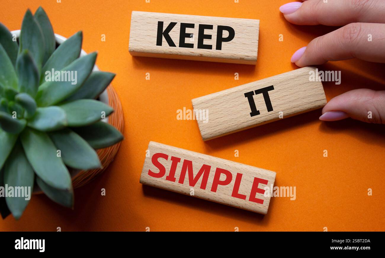 Symbole garder simple. Les mots conceptuels gardent la simplicité sur les blocs de bois. Main d'homme d'affaires. Beau fond orange avec plante succulente. Entreprise et Banque D'Images