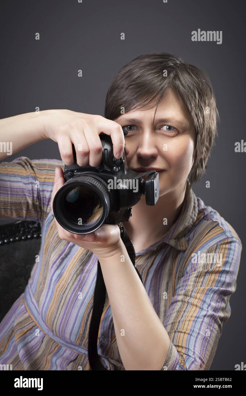 Femme photographe avec appareil photo ower gris bavground Banque D'Images