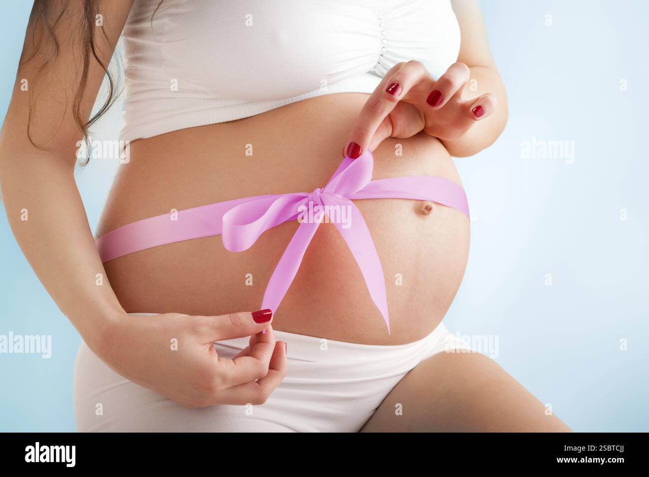 Ventre de beauté enceinte avec ruban rose. Troisième trimestre Banque D'Images