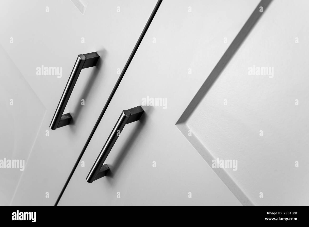 Vue détaillée et rapprochée des portes de garde-robe de chambre avec poignées en métal dans un style moderne à un angle, noir et blanc. Banque D'Images
