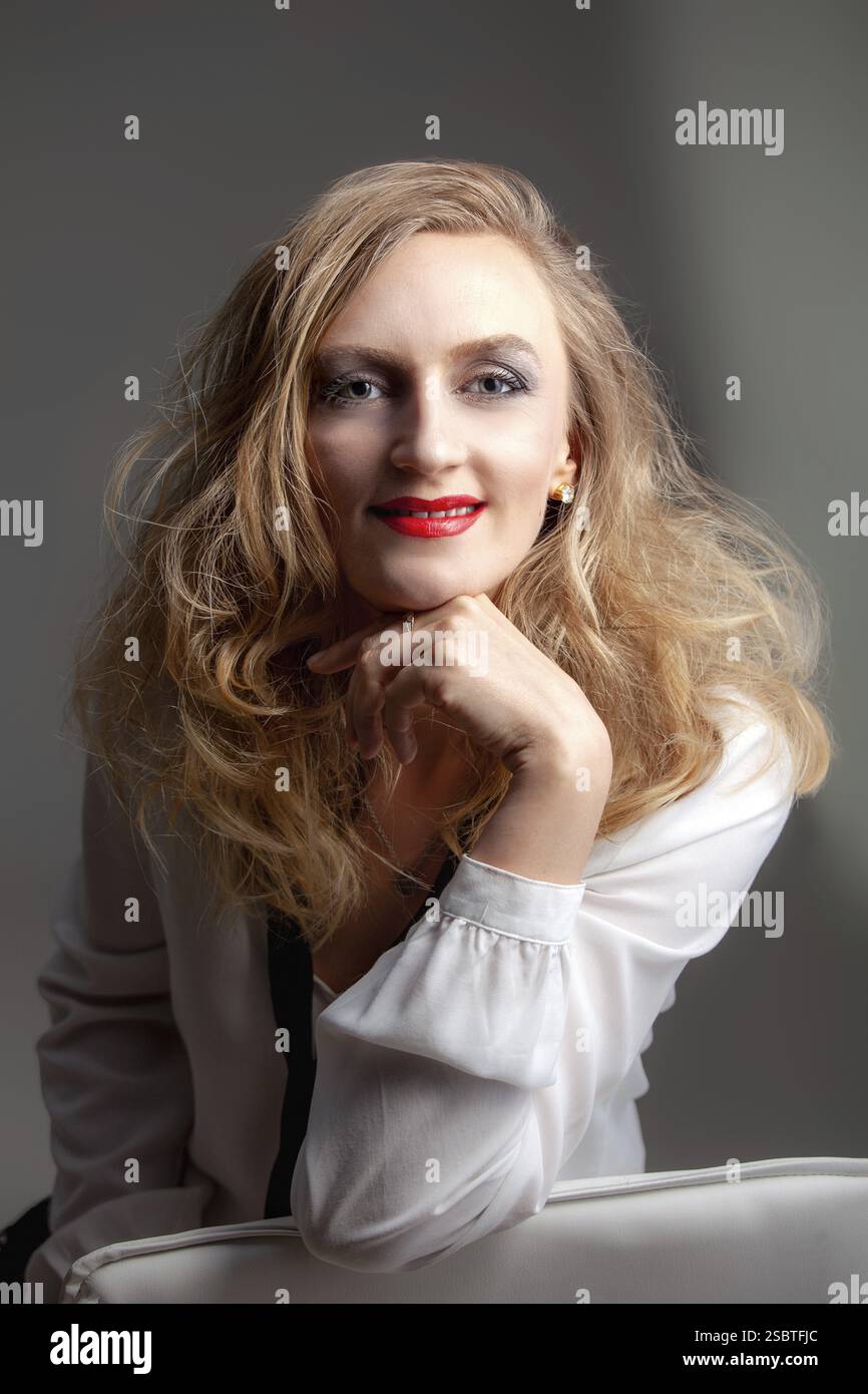 Portrait d'une femme aux cheveux blonds parfaits et maquillage. Sur fond gris Banque D'Images