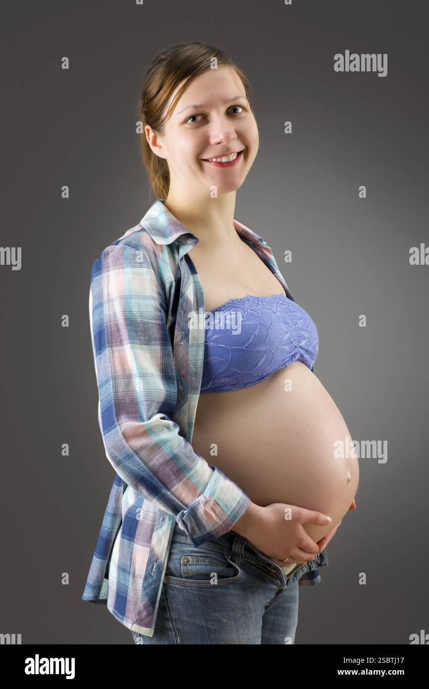 Heureuse jeune femme enceinte sur fond gris Banque D'Images