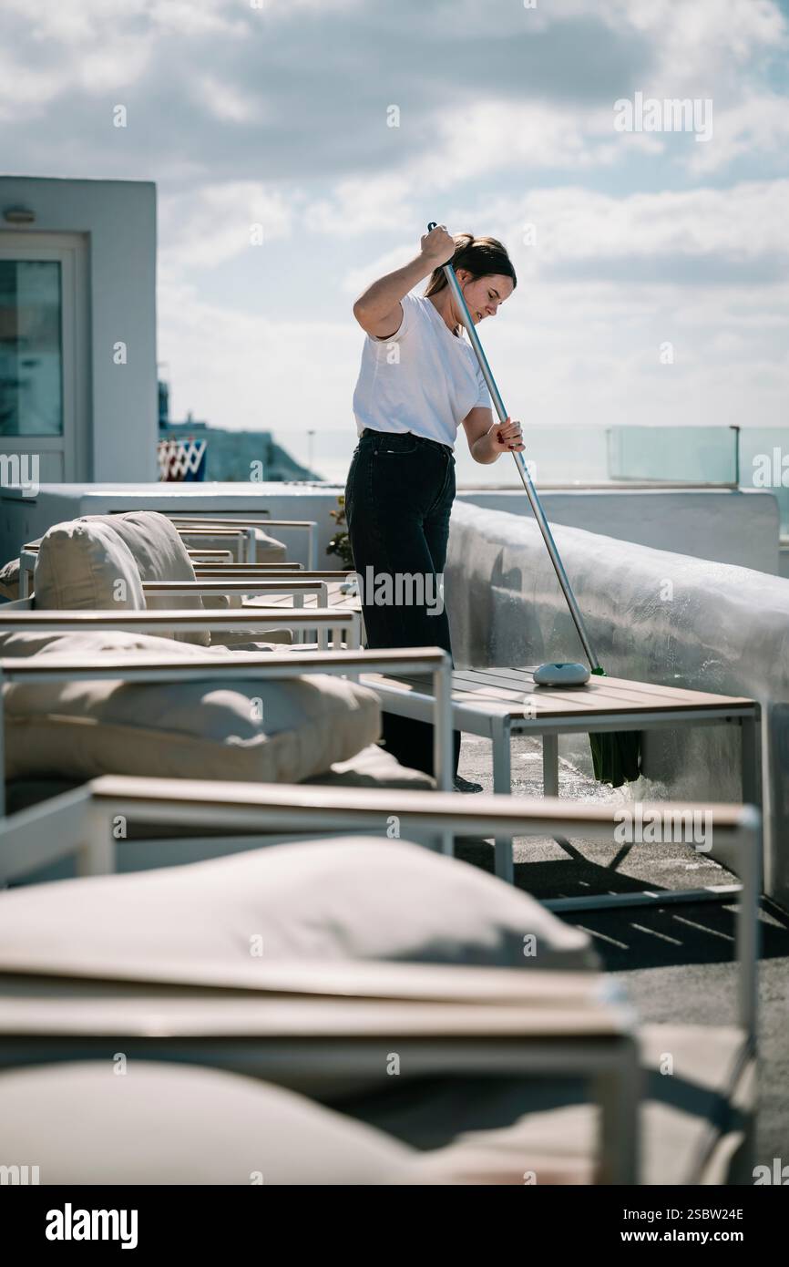 Une femme nettoyant la terrasse d'un hôtel à Santorin, Grèce Banque D'Images Une femme nettoyant la terrasse d'un hôtel à Santorin, Grèce Banque D'Images