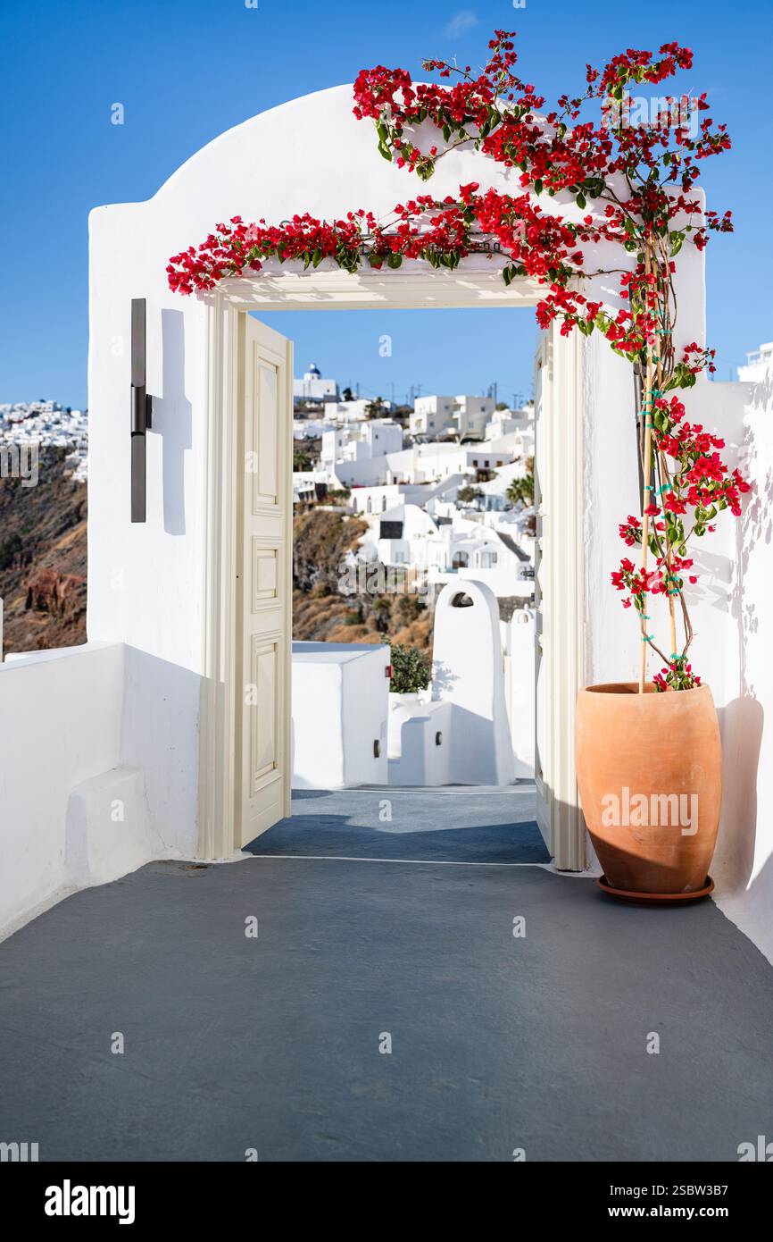 Vue sur les falaises de Santorin et le soleil à travers une arche avec une porte ouverte et bougainvilliers en fleurs, Cyclades, Grèce Banque D'Images