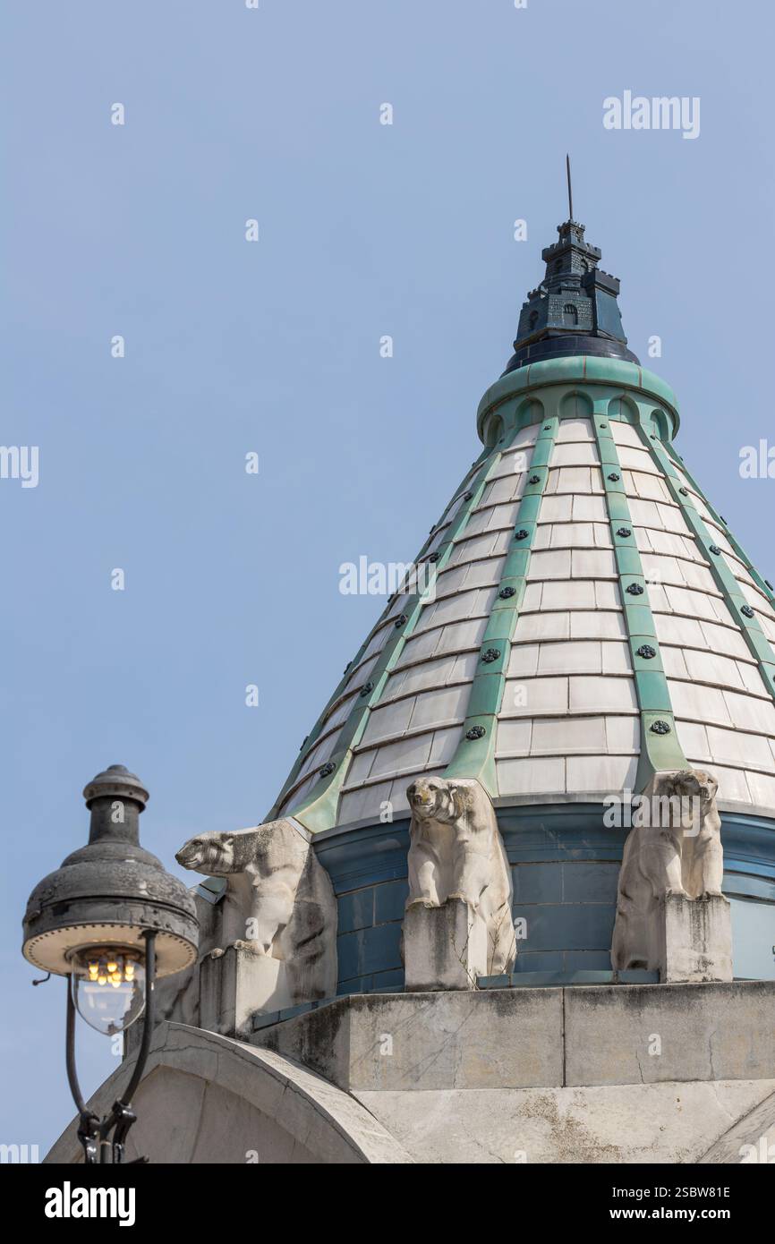 Gros plan d'un dôme architectural unique orné de sculptures et d'une lampe ornementale adjacente, placé contre un ciel bleu clair. Capture l'archit classique Banque D'Images