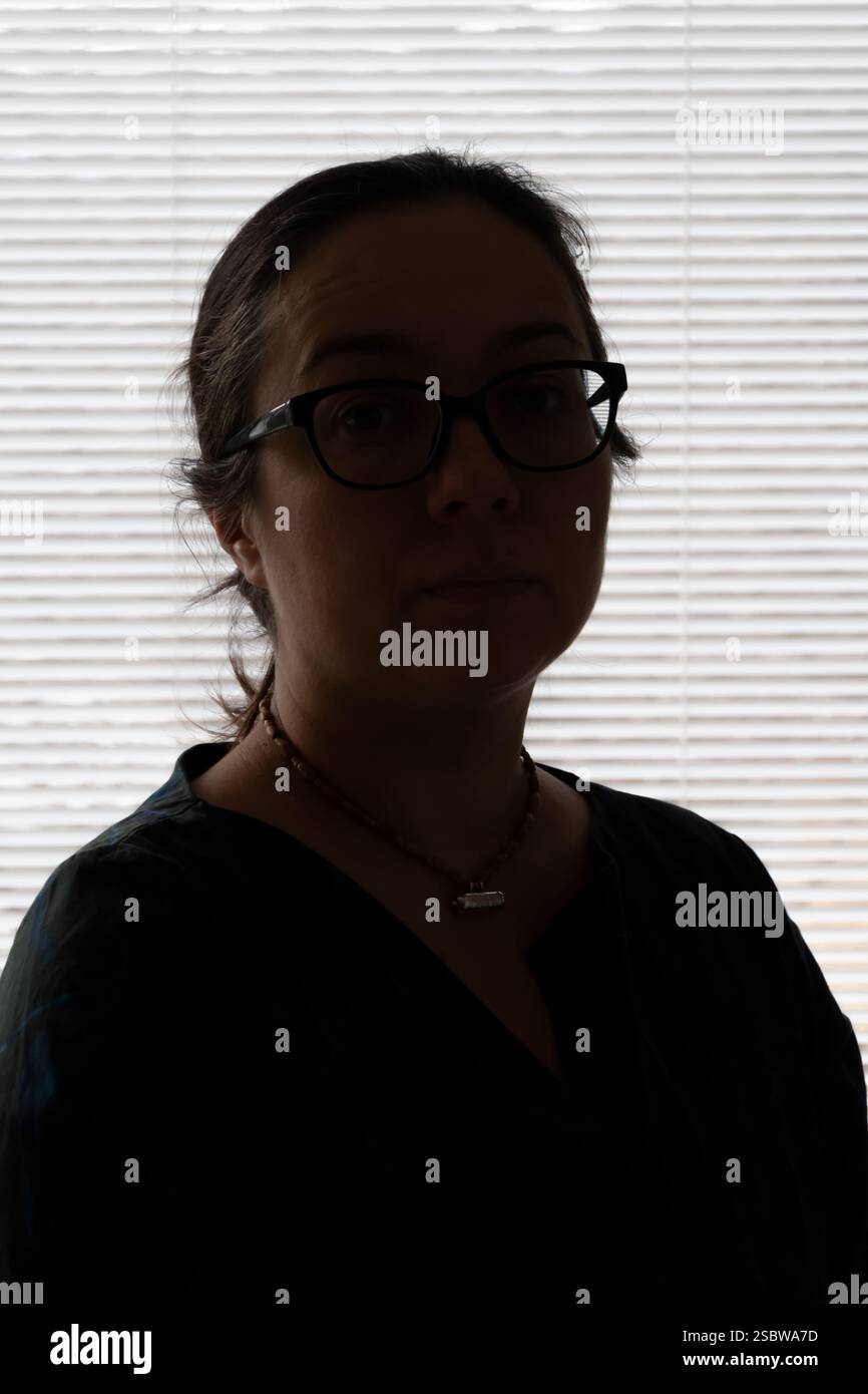 Silhouette sombre d'une femme devant la fenêtre, jeu artistique de lumière et d'ombre Banque D'Images