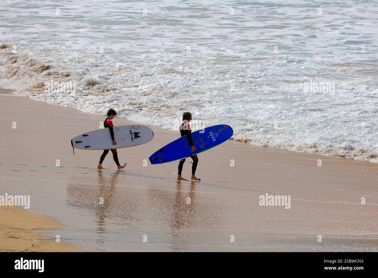 Couple portant des planches de surf vers la mer. Surf sur la plage de Piedra Playa, El Cotillo, Fuerteventura, Îles Canaries, Espagne. Prise en novembre 2024 Banque D'Images