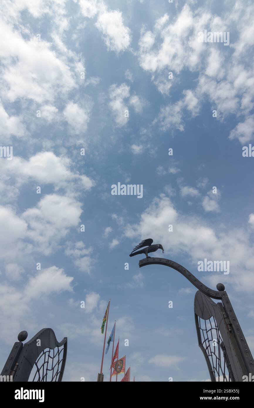 Le corbeau tient dans son bec un anneau. Beaux détails architecturaux d'un bâtiment historique sous un ciel dégagé avec des nuages éparpillés, accompagnés d'un b. Banque D'Images