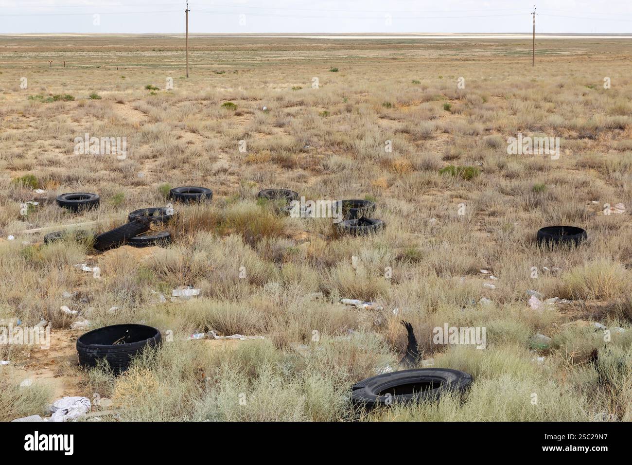 Les pneus abandonnés se dispersent dans un paysage sec et herbeux au Kazakhstan, mettant en évidence les problèmes de pollution dans les zones reculées. Banque D'Images