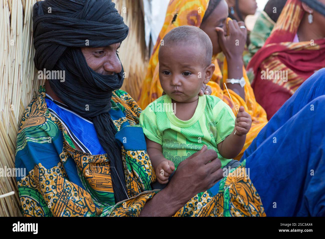 Camp de réfugiés maliens de Mentao, près de Gibo, dans le nord du Burkina Faso mai 2012 : un père touareg avec son bébé fils dans le camp. Les réfugiés, pour la plupart Touaregs, sont aujourd’hui plus de 60 000 au Burkina Faso seulement, et continuent d’arriver quotidiennement dans les camps, suite au chaos politique créé par le coup d’État du 22 mars 2012 par des officiers maliens subalternes. Photographie de Mike Goldwater Banque D'Images