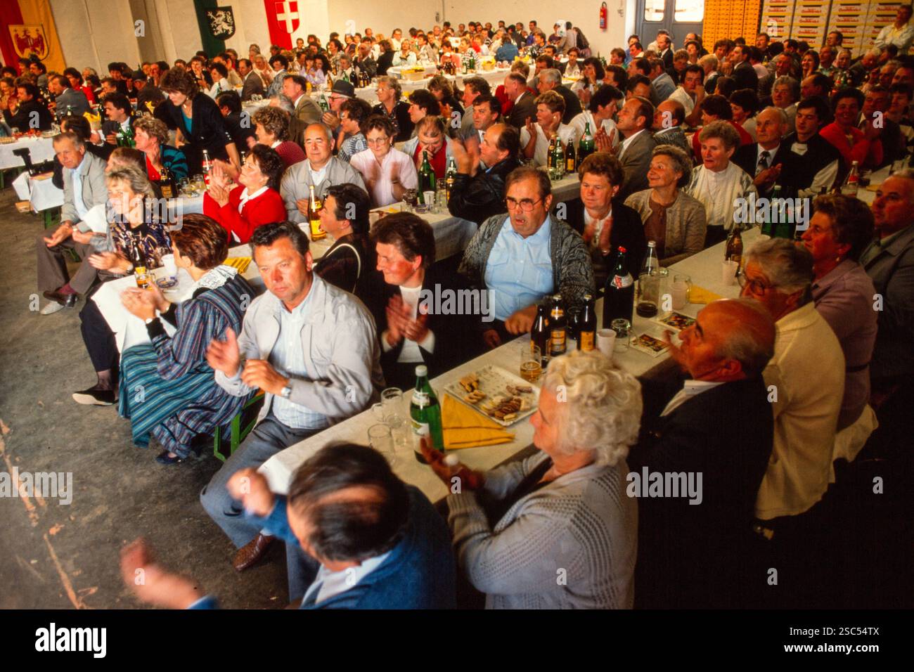 Grand rassemblement de personnes lors d'un événement social en Autriche avec des drapeaux et des tables décorées avec des boissons. Banque D'Images