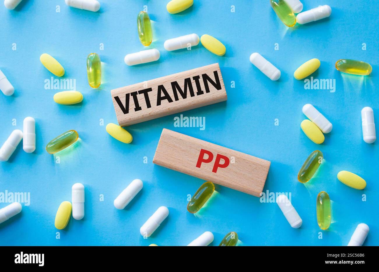 Symbole de vitamine PP. Mot concept Vitamin PP sur des blocs de bois. Beau fond rose avec des pilules. Concept de médecine et de vitamine PP. Copier l'espace Banque D'Images