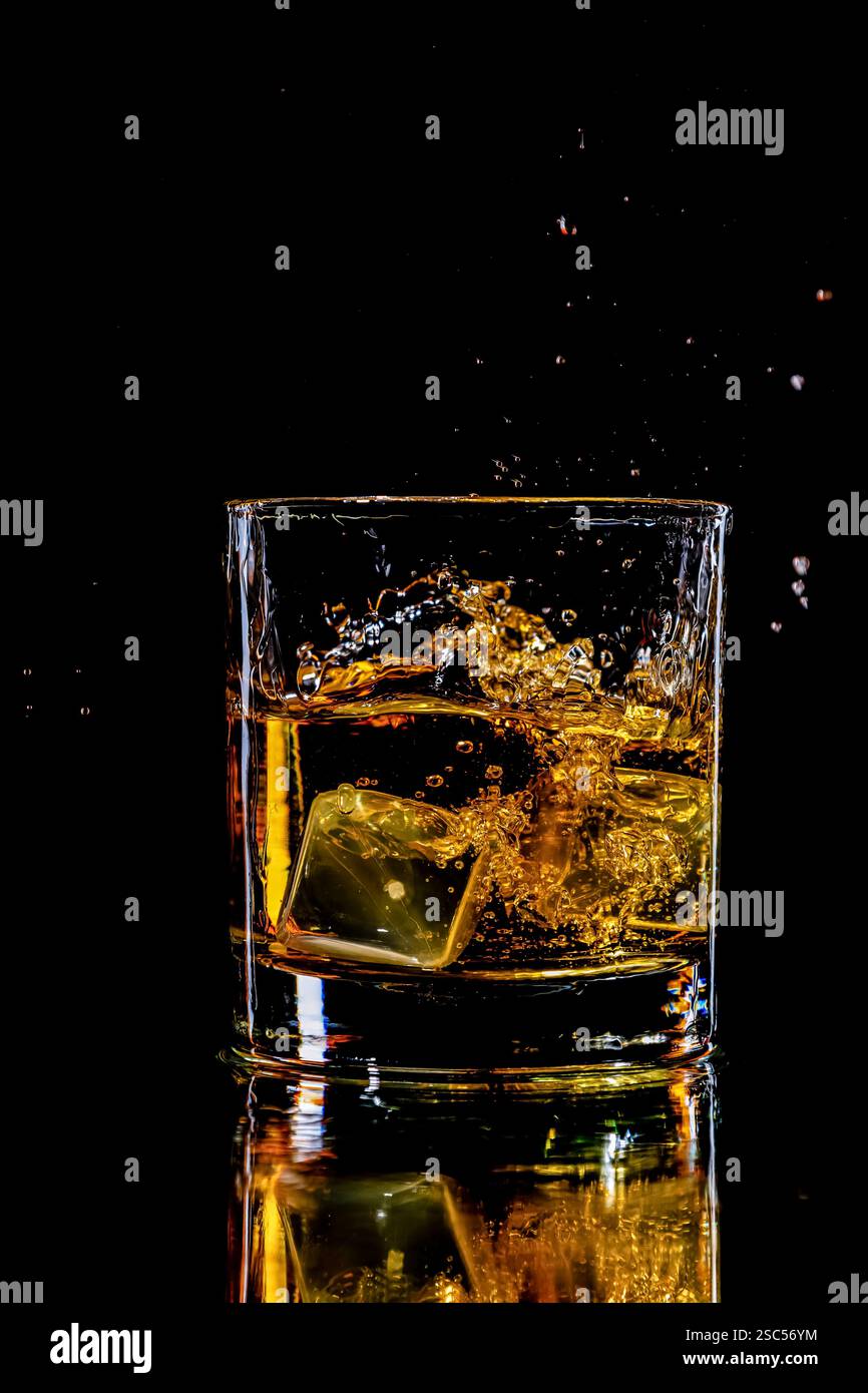 whisky éclabousser dans un verre avec deux glaçons Banque D'Images