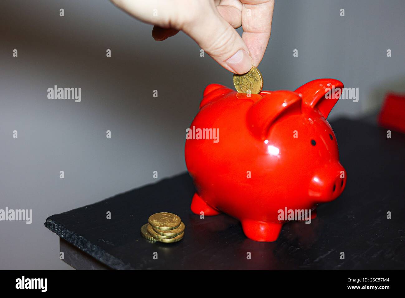 tirelire sur une table en bois tirelire rouge et main argent main jette pièce de monnaie dans tirelire Banque D'Images