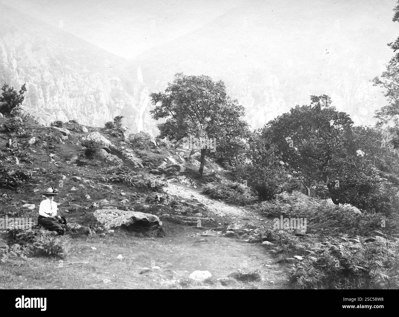 Une dame assise dans un paysage rocheux dans les chutes d'Aber, également connu sous le nom de Rhaeadr Fawr en gallois, situé près du village d'Abergwyngregyn, à environ deux miles au sud de Trefriw. La cascade est formée par l'Afon Goch dans les contreforts de la chaîne de montagnes Carneddau dans le nord du pays de Galles. C1900s, monochrome : d'une importante collection historique de photographies originales et inattribuées de l'albumen de la fin de l'époque victorienne au début de l'époque édouardienne : une tournée britannique comprenant le Staffordshire, le Warwickshire et le nord du pays de Galles. La qualité des originaux était variable et la plupart étaient autour de 108x165mm. Banque D'Images