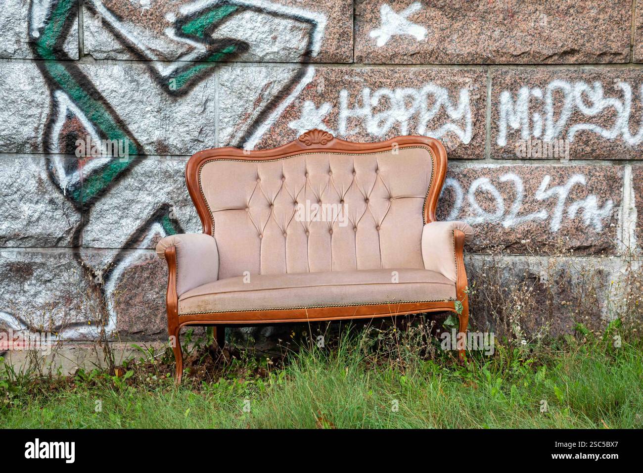 Canapé abandonné contre mur de pierre recouvert de graffitis dans le quartier de Vallila à Helsinki, Finlande Banque D'Images