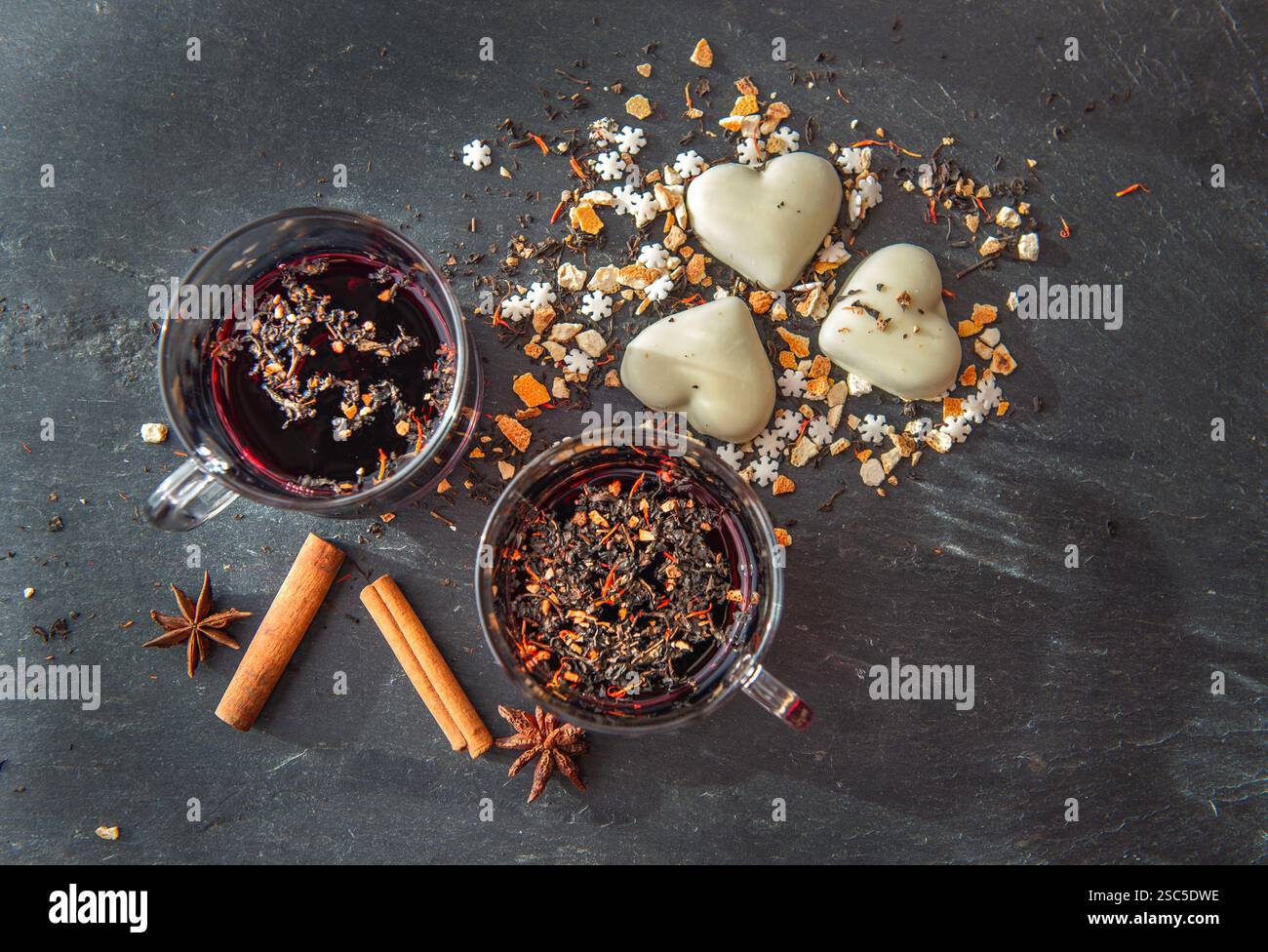 vue de dessus sur le vin chaud dans deux verres avec des biscuits en forme de coeur et des épices disposés sur un fond d'ardoise grise Banque D'Images