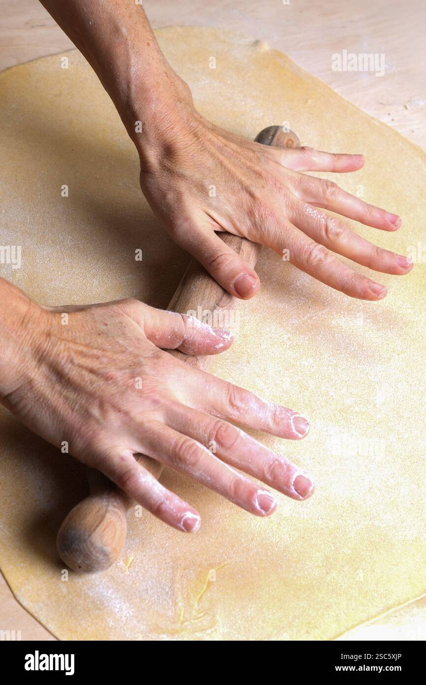 Préparation de pâtes maison en Toscane. L'image montre les mains d'une femme roulant, façonnant et coupant la pâte à pâtes fraîche, pappardelle et gnocchi. Banque D'Images