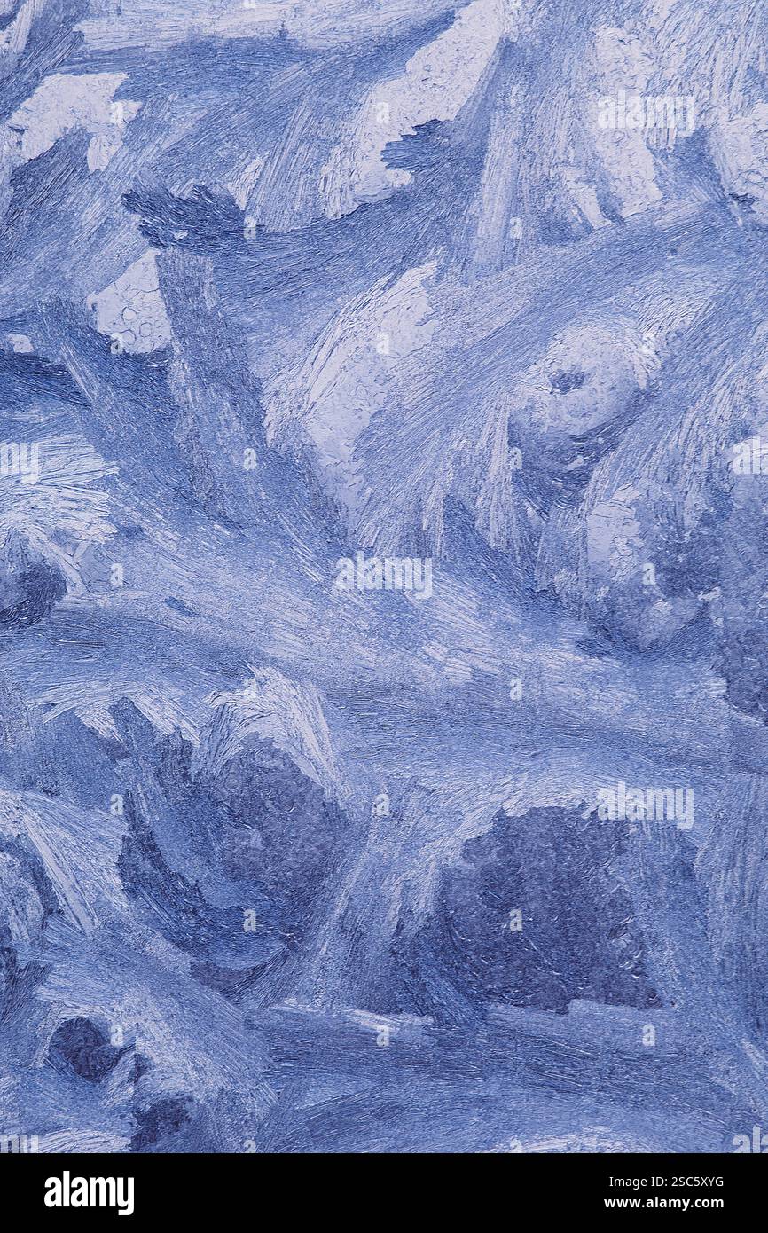 Gros plan des motifs givrés sur le verre, créés par des températures glaciales. Cristaux de glace abstraits et formations de gel ressemblant à des paysages hivernaux Banque D'Images