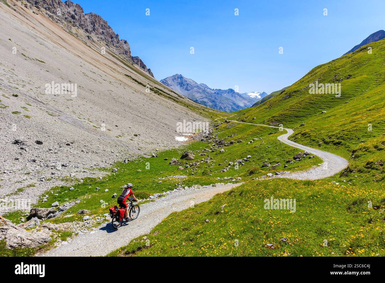 Homme touriste vélo sur MTB vélo avec bagages dans les sacoches dans la belle vallée d'Alpisella le jour ensoleillé d'été, Alpes montagnes, Italie Banque D'Images