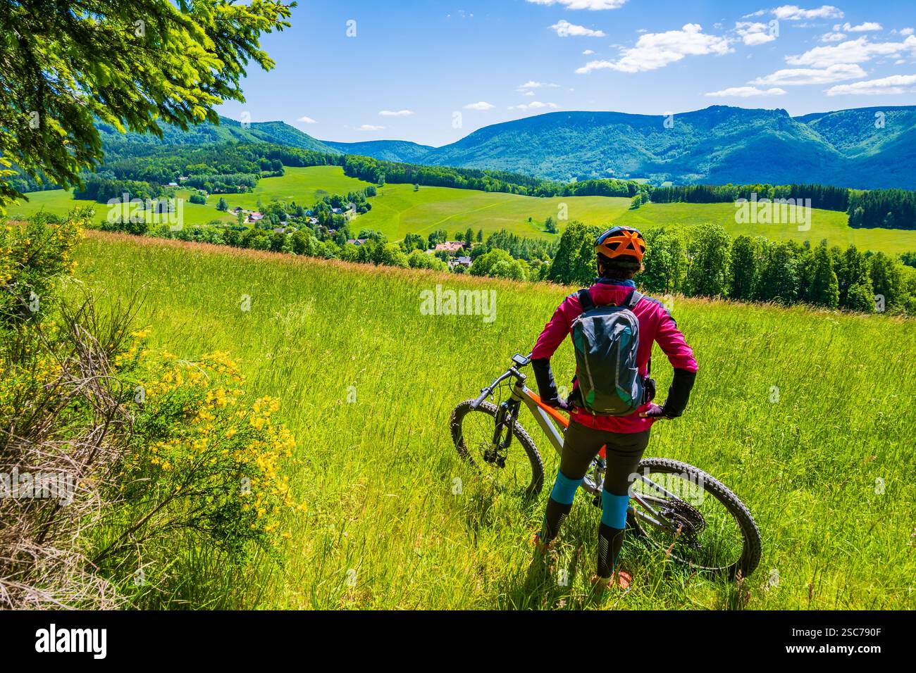 Femme avec sac à dos reposant de vélo de montagne sur un sentier de piste unique parmi les collines verdoyantes dans les montagnes de Jizera, Singletrk pod Smrkem République tchèque Banque D'Images