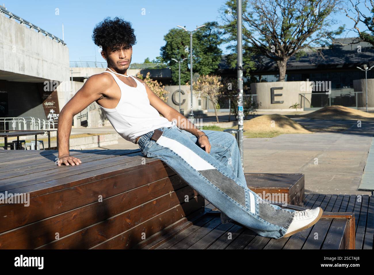 Jeune homme latino posant sur une plate-forme en bois dans un carré Banque D'Images