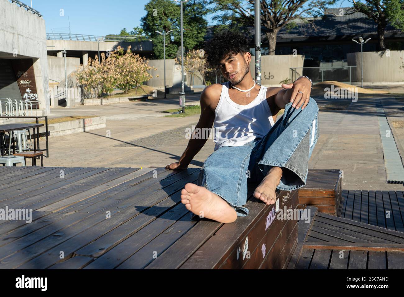 Jeune homme latino posant sur une plate-forme en bois dans un carré Banque D'Images