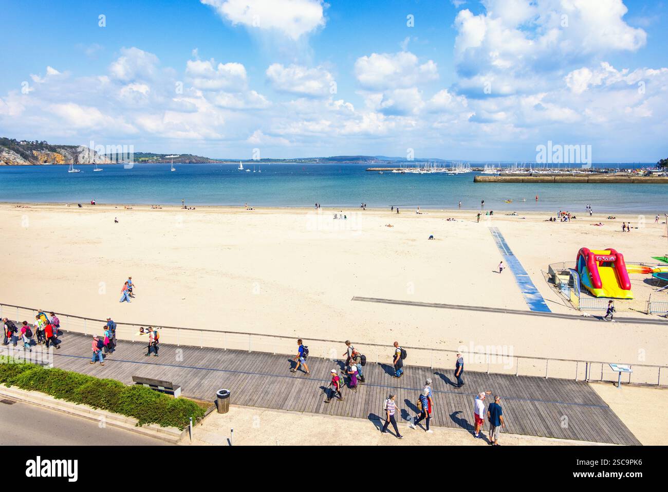 Les gens marchant sur la promenade par une plage de sable avec une belle vue sur le paysage marin Banque D'Images