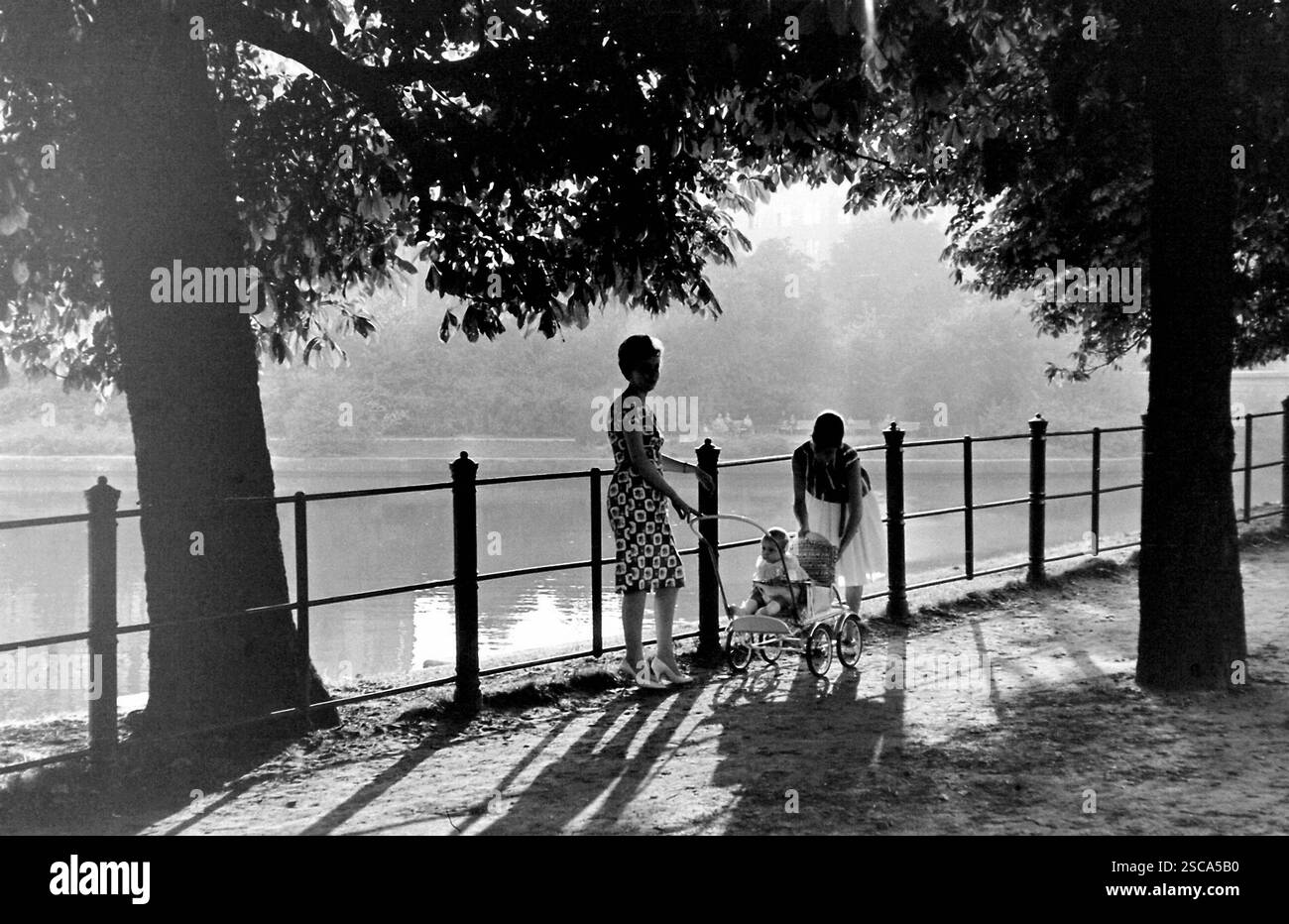 Les femmes et enfants avec buggy, robe et hauts talons de prendre une marche au Landwehrkanal à Berlin. Banque D'Images