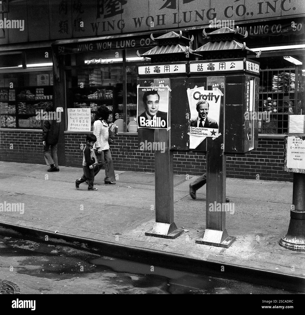 Les passants passent devant les affiches électorales sur les cabines téléphoniques dans le quartier chinois, la ville de New York. Banque D'Images