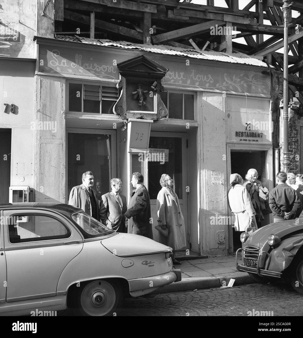 Voitures (Citroën 2CV) et personnes devant un restaurant de la rue Mouffetard à Paris. Banque D'Images