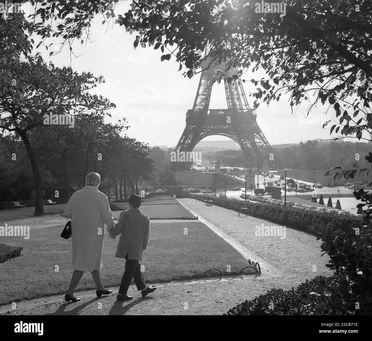 La Tour Eiffel et le Chomp de mars à Paris. Côté gauche de l'image une femme avec capuche de pluie et un garçon avec chapeau et manteau. Banque D'Images
