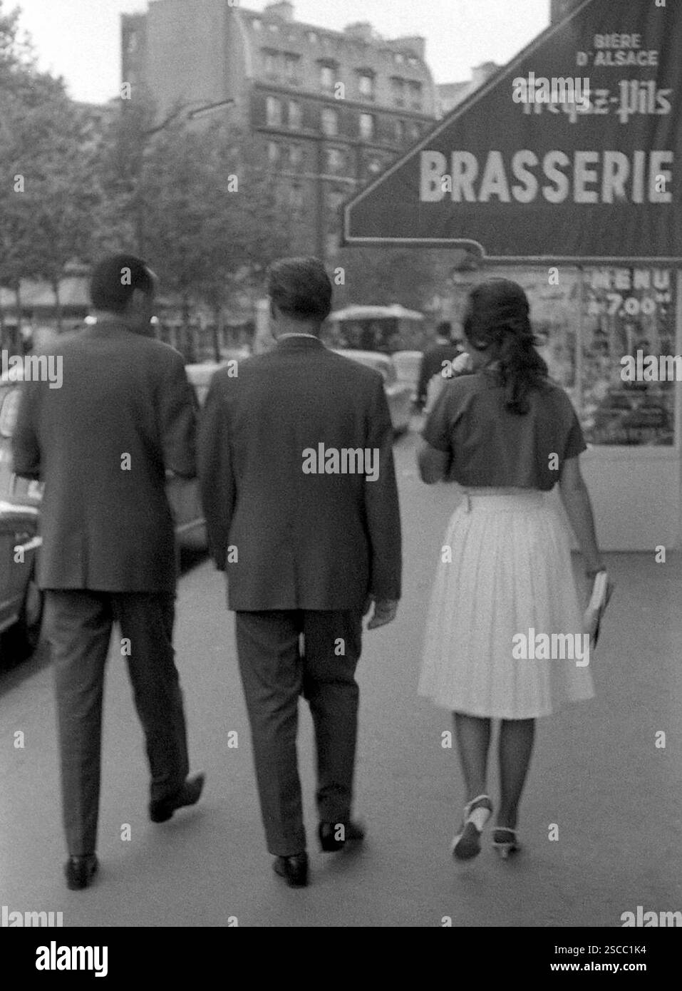 Des hommes portant des costumes et une femme portant une jupe et des talons hauts devant une Brasserie à Paris. Banque D'Images