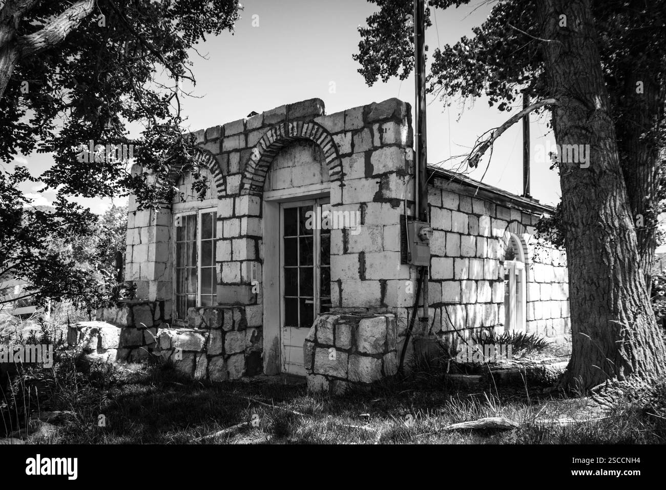 Un vieux bâtiment abandonné avec une architecture de style arqué unique autour des fenêtres et des portes avant. Banque D'Images