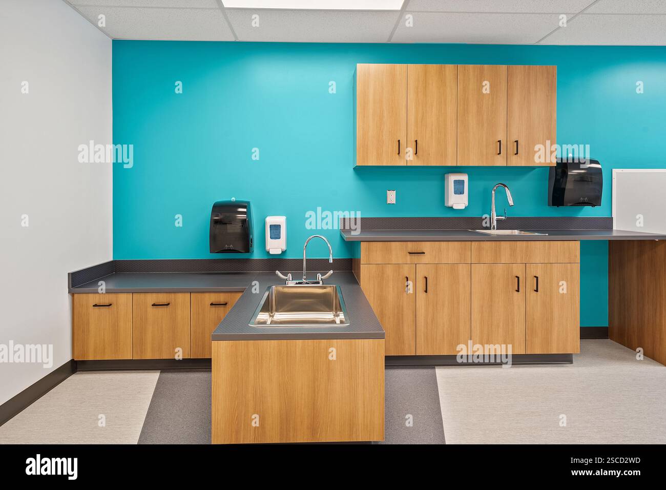 Une cuisine avec un mur bleu et des armoires en bois. L'évier est au milieu de la pièce Banque D'Images