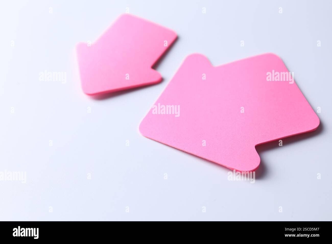 Flèches en papier rose sur fond blanc, gros plan Banque D'Images