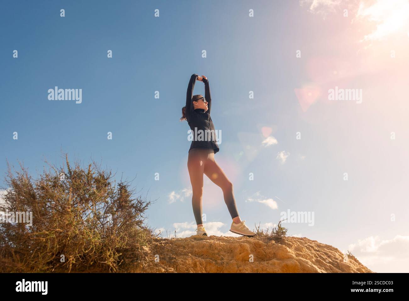 femme sportive debout au sommet d'une falaise avec les bras levés Banque D'Images femme sportive debout au sommet d'une falaise avec les bras levés Banque D'Images