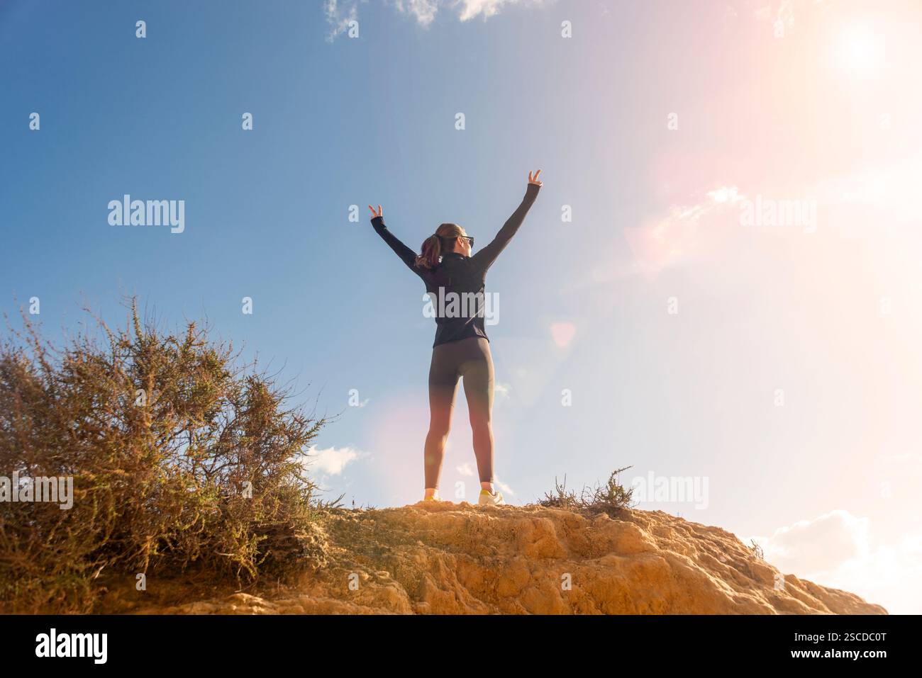 femme sportive debout au sommet d'une falaise avec les bras levés Banque D'Images femme sportive debout au sommet d'une falaise avec les bras levés Banque D'Images