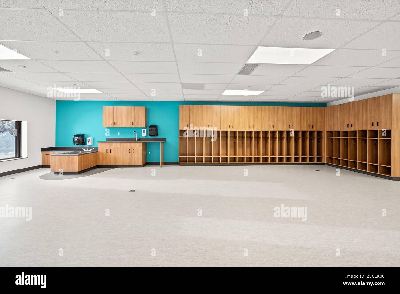 Une grande pièce vide avec un mur bleu et des armoires en bois. La pièce est vide et a un look propre et organisé Banque D'Images