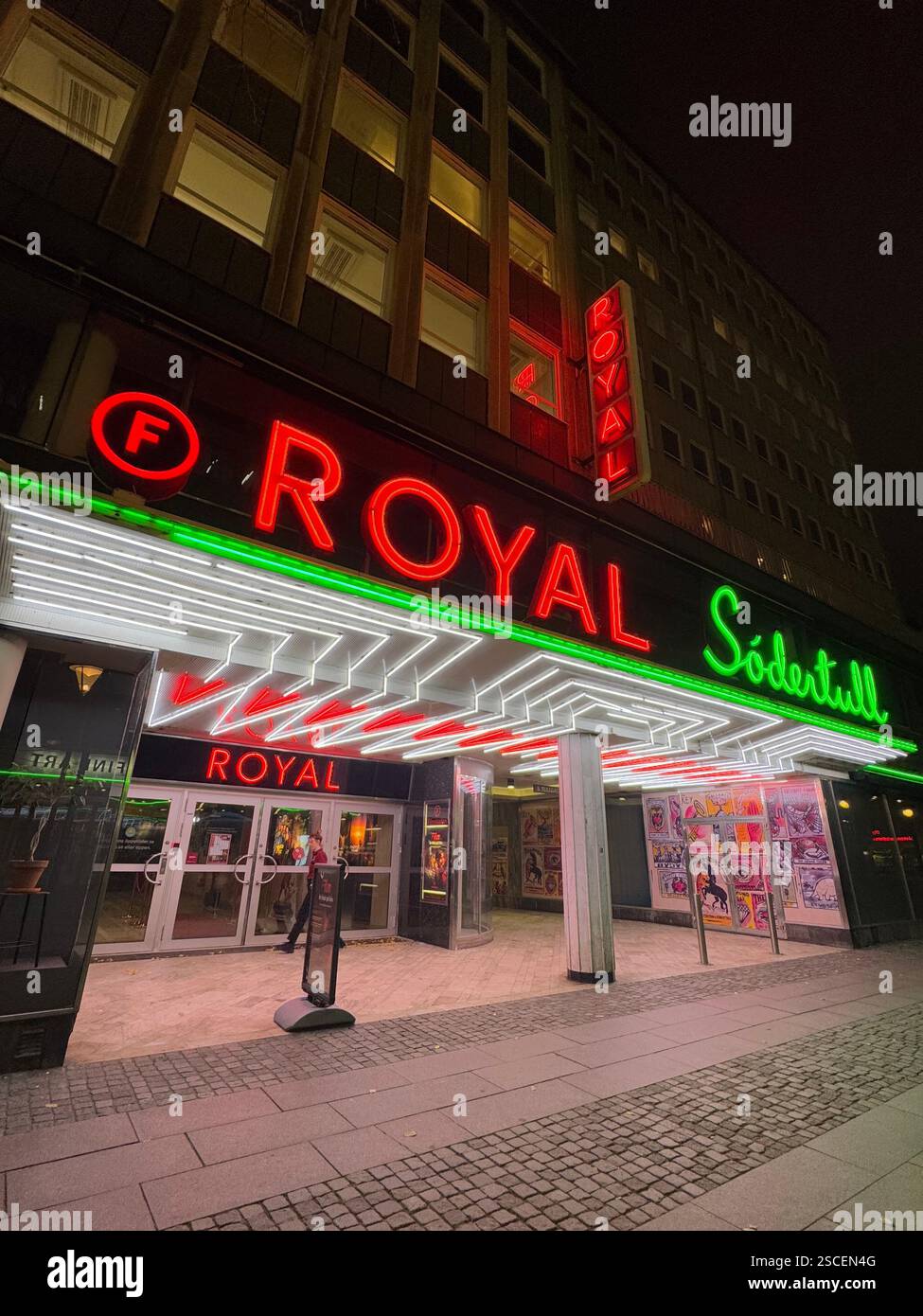 Un néon rétro brillant en rouge, vert et blanc sur un cinéma historique à Malmö, en Suède, projetant une lueur nostalgique dans une rue froide et solitaire la nuit. - Image de stock capturée avec un smartphone
