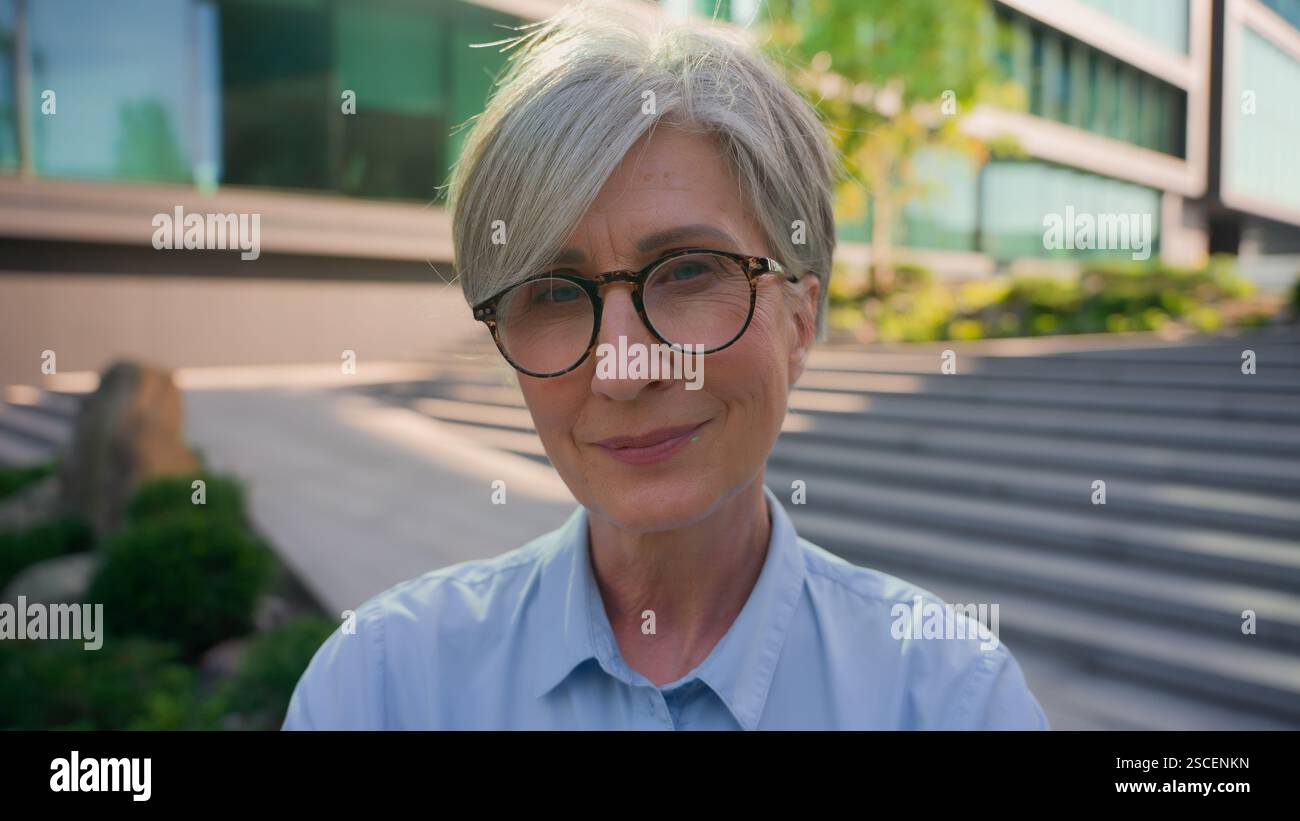 Souriant réfléchi rêve adulte mature femme caucasienne senior vieille femme d'affaires d'âge moyen en dehors de la femme d'affaires réussie femme âgée femme joyeuse Banque D'Images