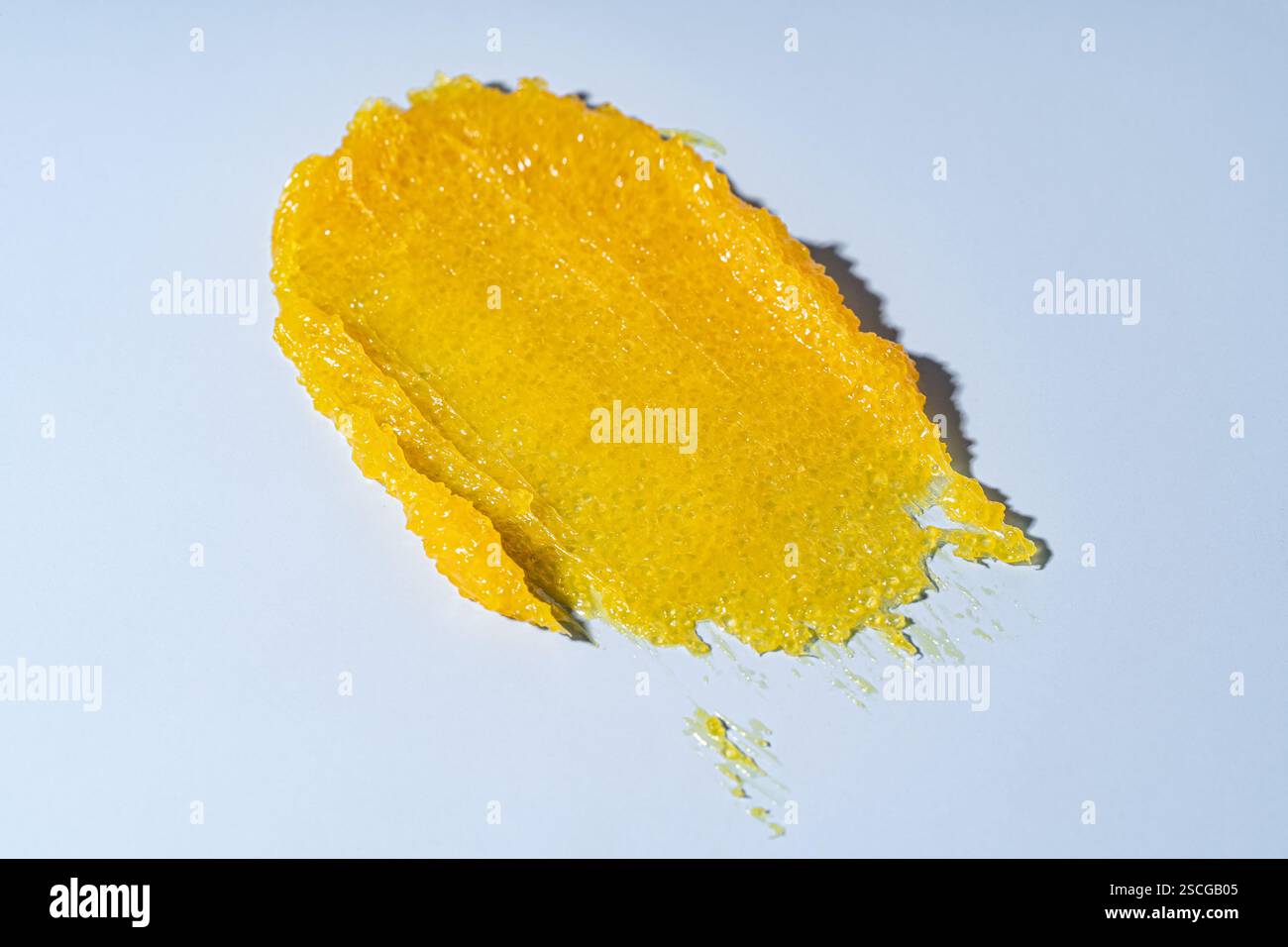 Soin de la peau gommage jaune, frottis sur fond bleu. Produit cosmétique texturé de beauté, glisser-déposer en gros plan Banque D'Images