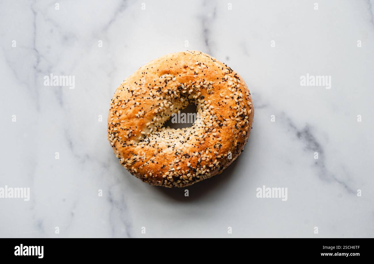 Vue de dessus de bagel unique tout sur fond de marbre blanc. Banque D'Images