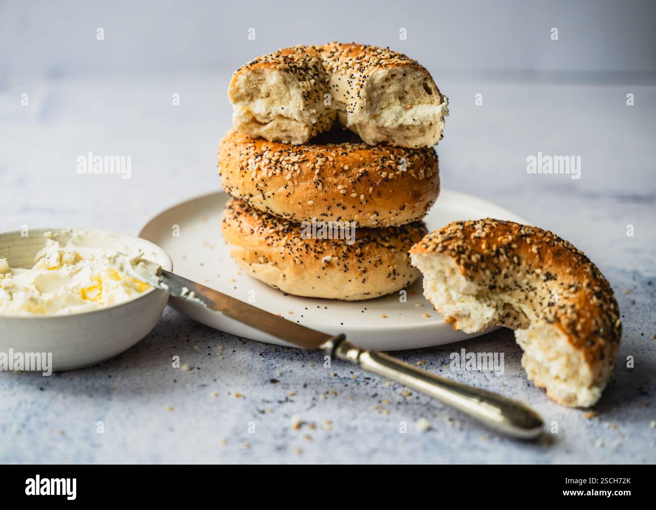 Gros plan d'une pile de tout bagels avec du fromage à la crème sur une assiette. Banque D'Images