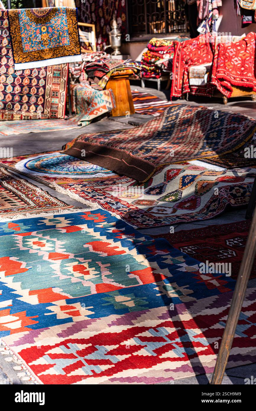 Une collection vibrante de tapis et de textiles géorgiens traditionnels exposés dans un marché en plein air à Tbilissi, en Géorgie. Les motifs complexes et col audacieux Banque D'Images