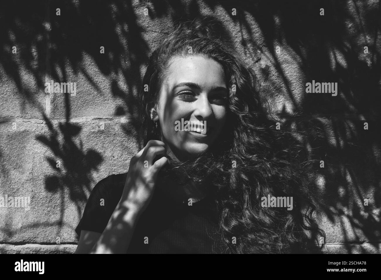 Portrait en échelle de gris Gen Z, fille souriante dans le soleil d'été et les ombres Banque D'Images