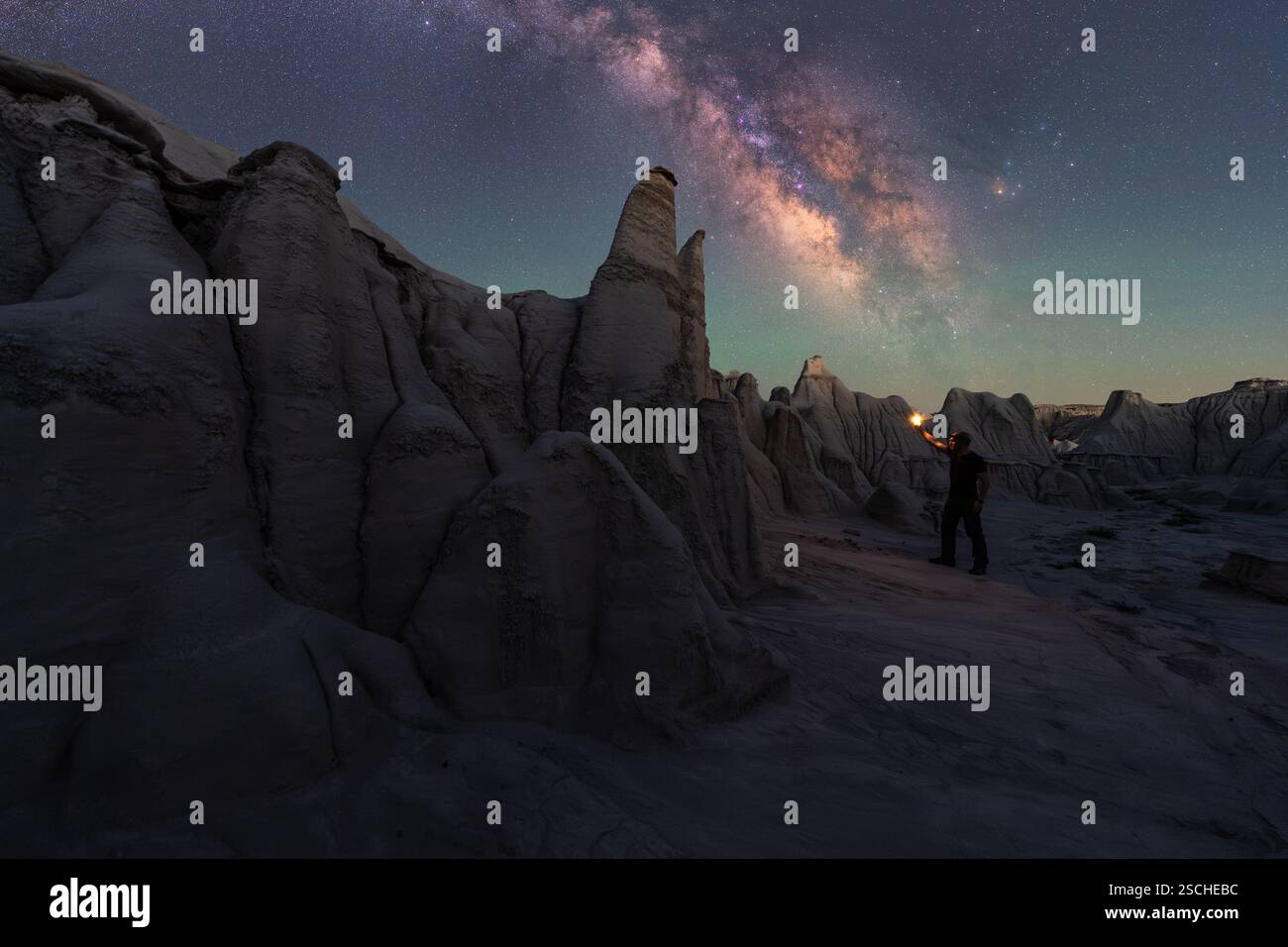 Une vue imprenable sur les structures en grès de Goblin Valley sous un ciel nocturne captivant. Une figure solitaire illumine la scène, améliorant le b cosmique Banque D'Images