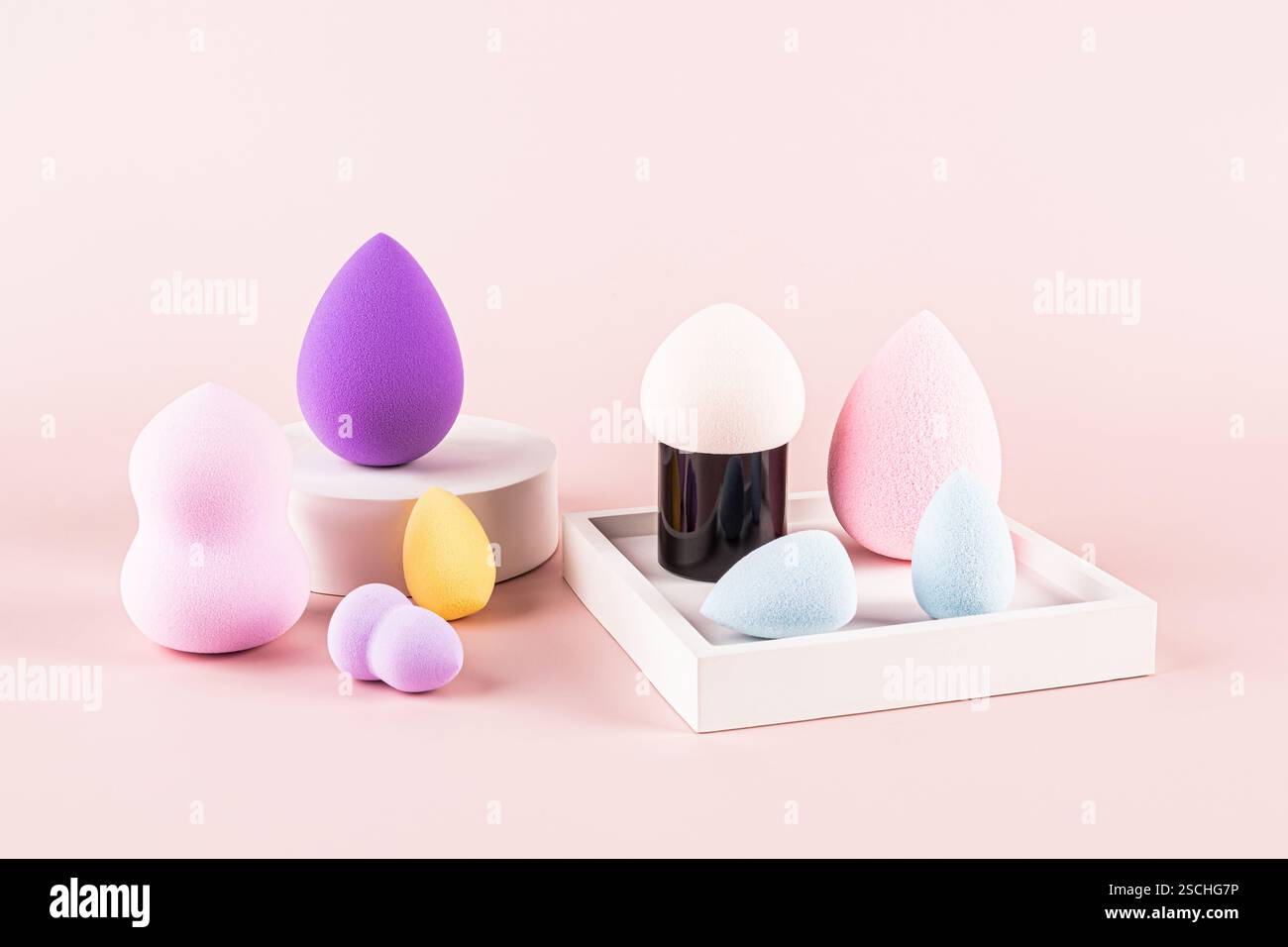 Diverses éponges de maquillage colorées et un mélangeur de beauté arrangé soigneusement. L'image présente différentes formes et tailles d'éponges, présentées sur une lumière p Banque D'Images