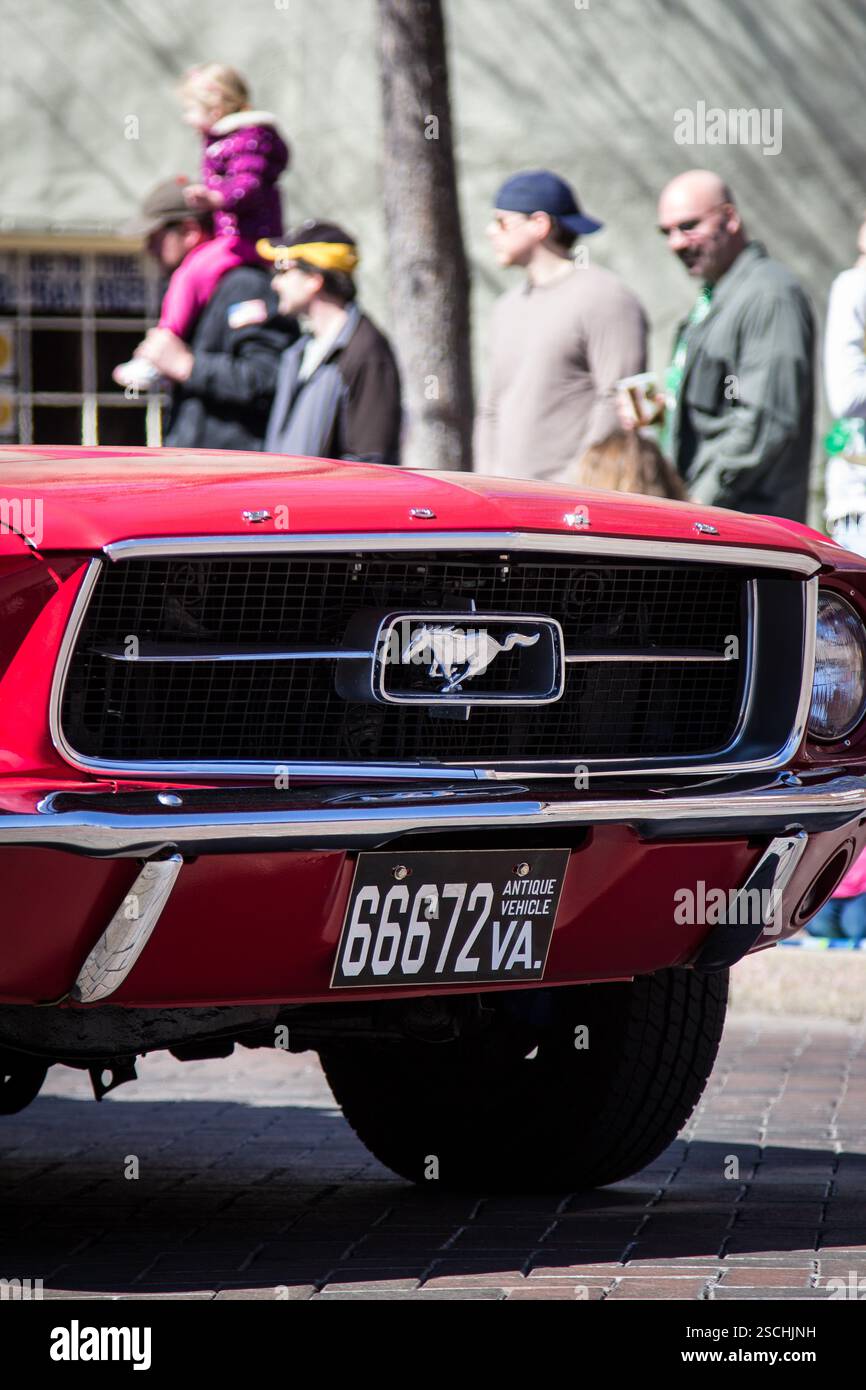 Mustang classique rouge (66672 va), probablement dans un défilé, avec des gens regardant. Banque D'Images