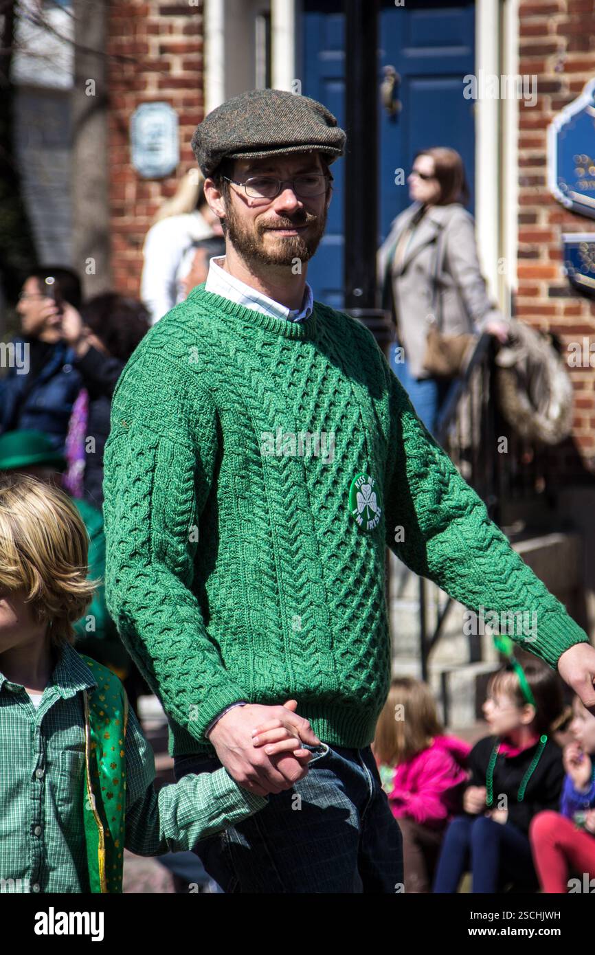 Père et enfant se tiennent la main dans le défilé de la fête de Patrick. Porter une tenue verte. Banque D'Images